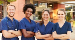 nurses stand smiling near a hospital entrance