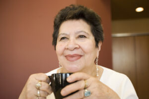 a senior smiles drinking coffee