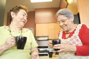 two seniors laugh over coffee