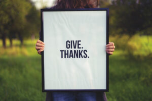 a person holding a sign that reads "give. thanks."