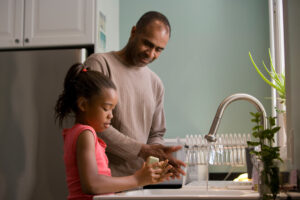 an adult helps a child wash their hands