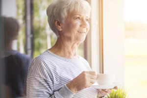 a senior smiles while holding a coffee cup