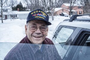 a senior with a WWII Korea Veteran heat on smiles as he enters a car